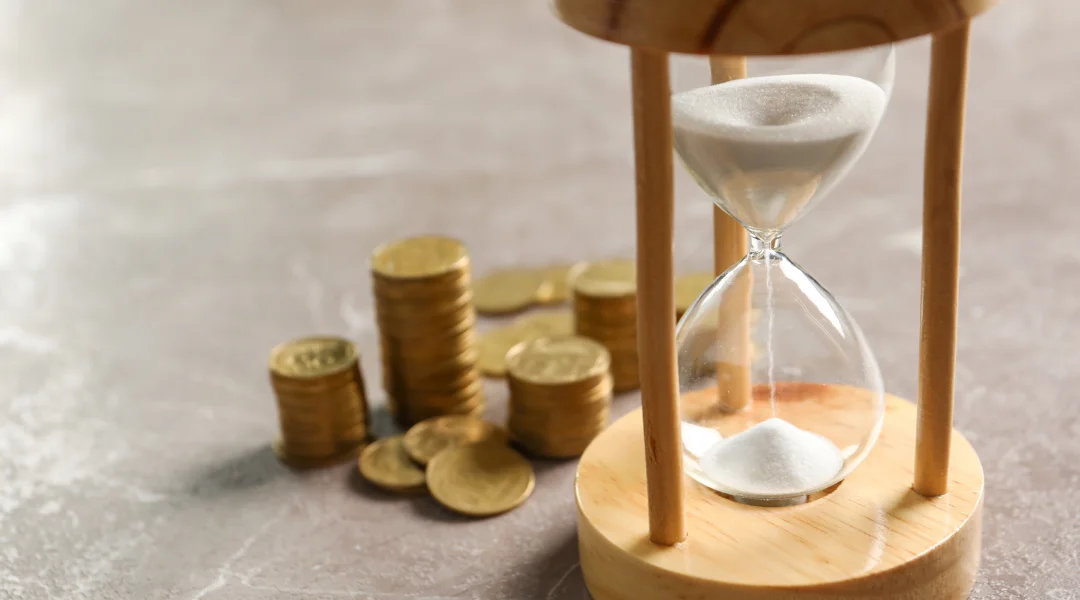 An hourglass filled with coins and sand, symbolizing time and finance, with a note about loans available seven days a week.