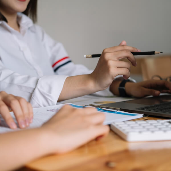 Deux personnes collaborent sur un ordinateur portable à un bureau, discutant de l'aide financière.