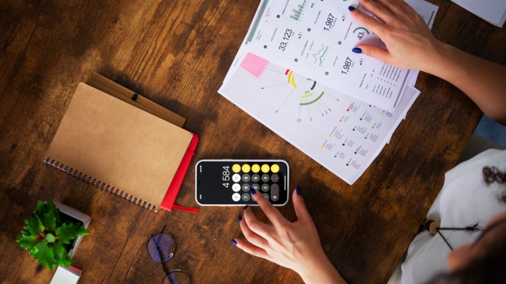 Femme d'affaires utilisant une calculatrice sur un bureau, préparant une consolidation de dettes.