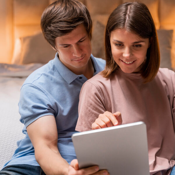 Un homme et une femme assis sur un lit, regardant un tableau ensemble, discutent d'un prêt rapide en ligne.
