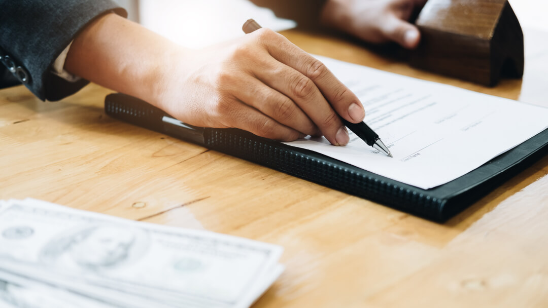 Un homme d'affaires signe un contrat tout en tenant des billets de banque, illustrant un prêt accessible malgré un faible crédit.