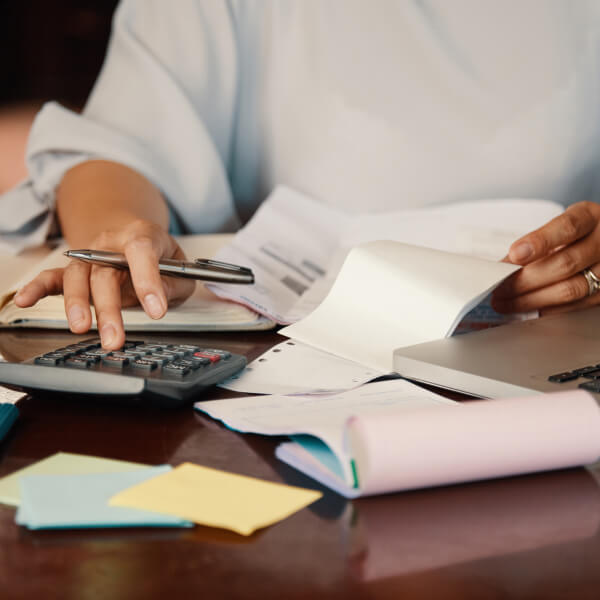 A man works on his laptop while using a calculator.