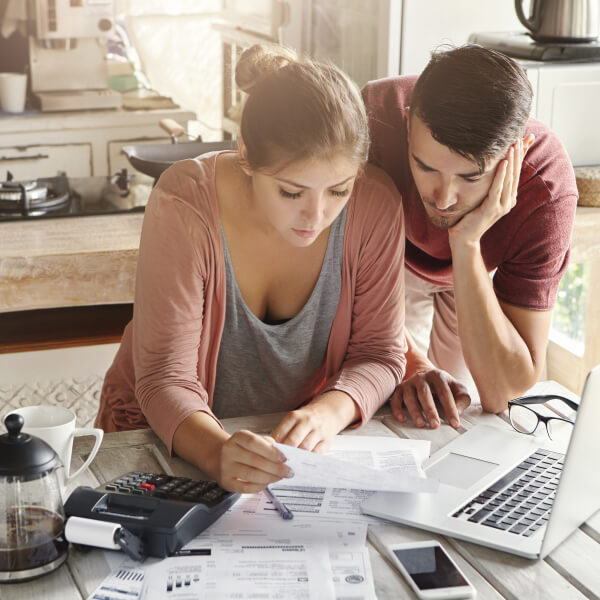 A man and a woman examine documents on a laptop, discussing the rise of microloans.