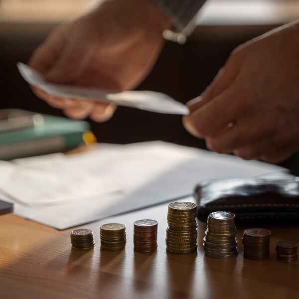 Une personne tient un papier et des pièces de monnaie, illustrant la recherche d'aide financière d'urgence.