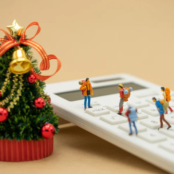 Christmas tree with people calculating expenses for a holiday loan on a calculator.