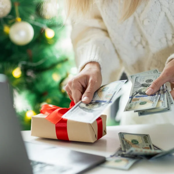 A woman counts money in front of a laptop, likely reviewing her finances for a Christmas loan.