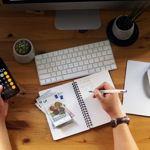 Un homme utilise une calculatrice et un stylo pour simuler des prêts et calculer des montants d'argent.