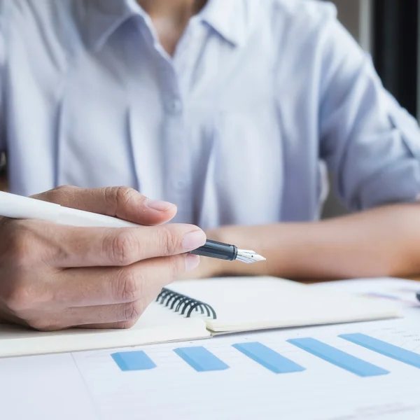 Businessman writing financial plans on paper with a pen, focused on organizing his financial strategy.