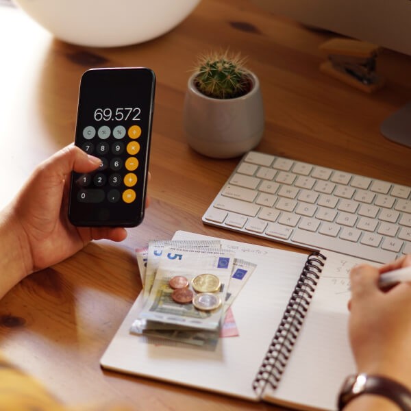 Hand using a calculator and taking financial notes, illustrating understanding of an emergency loan with no documentation required.