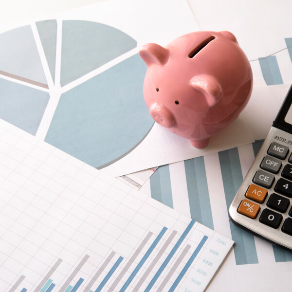 Piggy bank placed on financial charts with a calculator, representing the increase in interest in emergency loans in Canada.